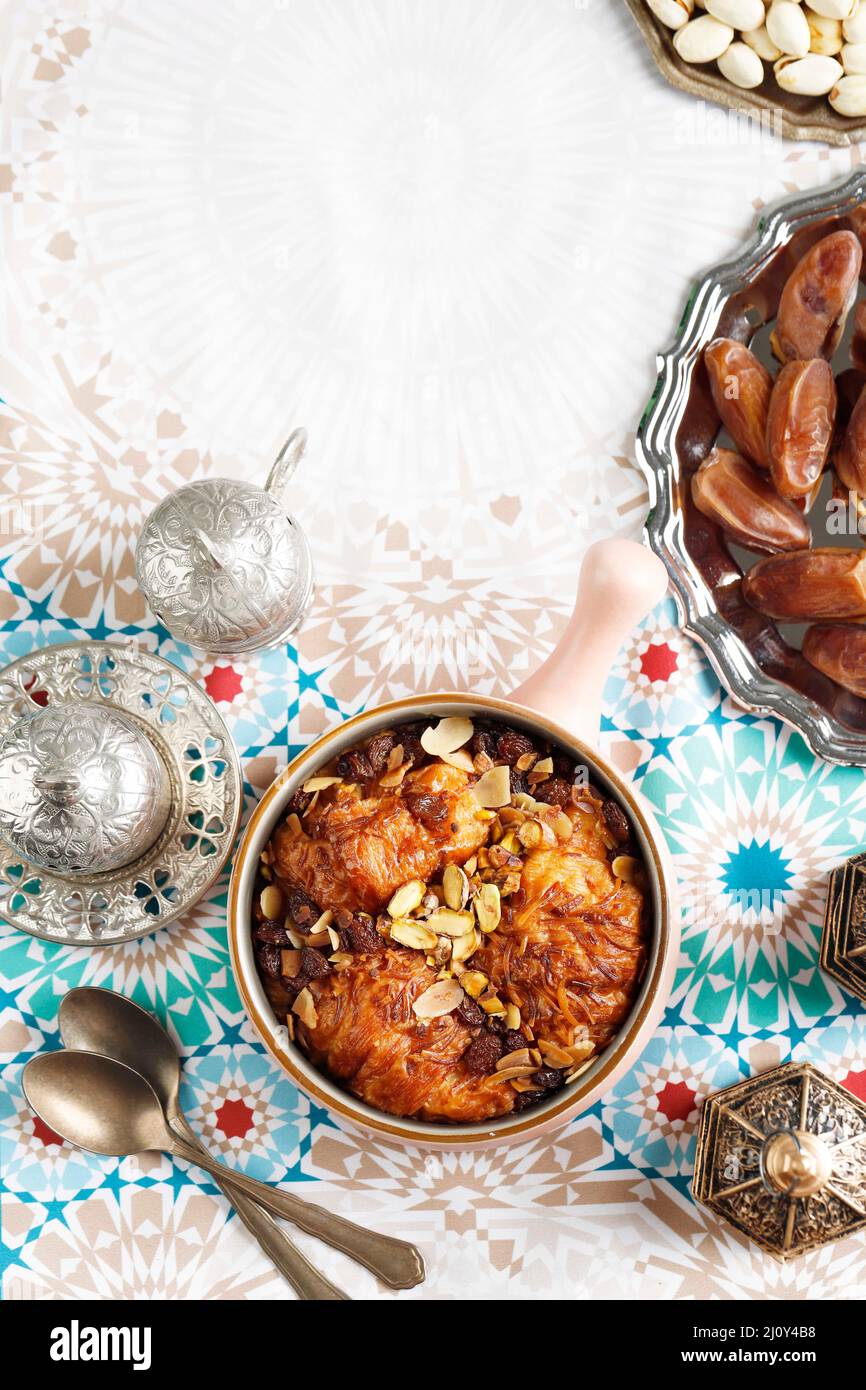 Oum Ali oder um Ali, ägyptisches Dessert nahöstliche Küche. Serviert mit Tee, Nüssen und Datteln. Draufsicht. Konzept Ramadan Dessert Süß Stockfoto