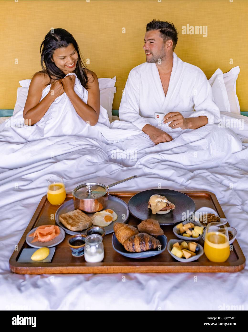 Mann und Frau frühstückten im Bett, Paar frühstückten mit Kaffeebrot und Obst im Schlafzimmer Stockfoto