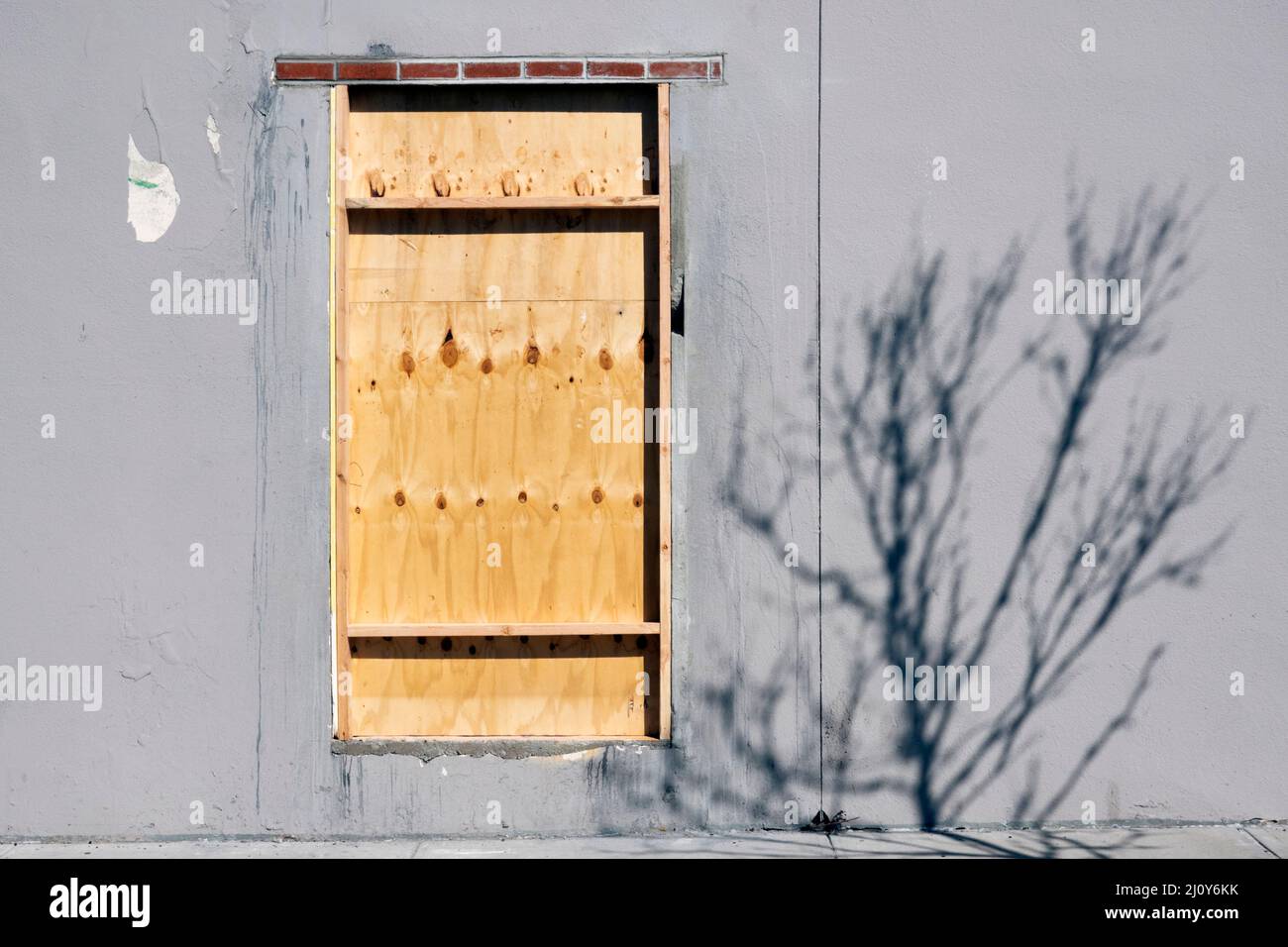 STADTLANDSCHAFT Eine Holztür auf einer leeren Wand mit etwas Licht und Schatten. Auf dem Francis Lewis Blvd in Flushing, Queens, New York. Stockfoto