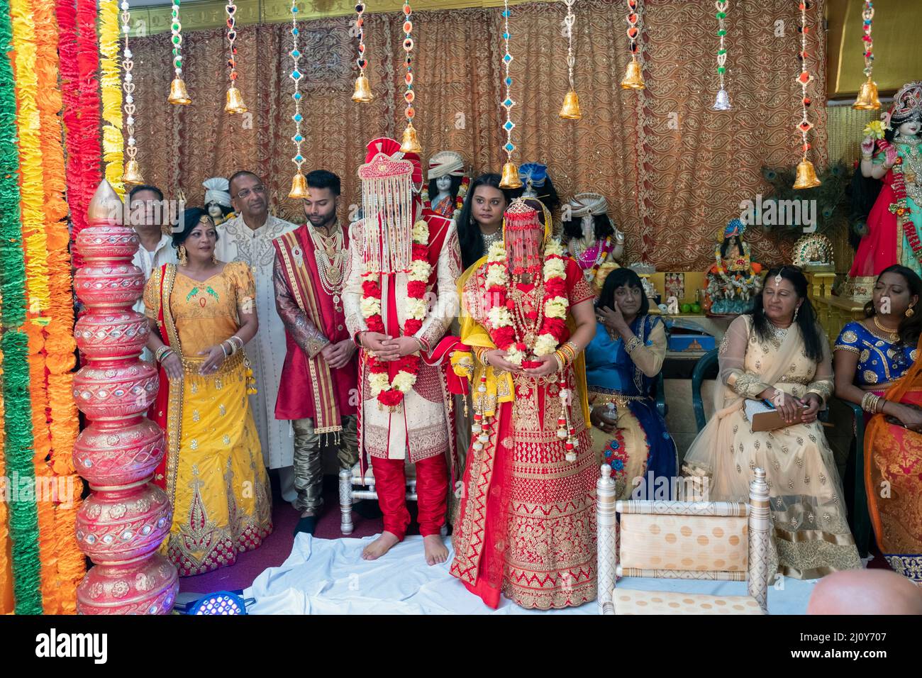 HINDUISTISCHE HOCHZEIT die Braut, der Bräutigam, die Begleiter, die Familie und Freunde während der Hochzeitszeremonie. In einem Tempel in Queens, New York City. Stockfoto