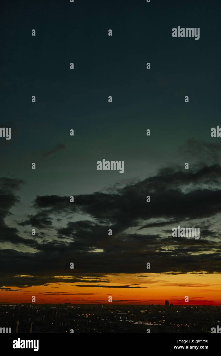 Atemberaubende Luftaufnahme der rot-orange Sonnenuntergang Stadtlandschaft auf blauem Himmel und Wolken. Futuristische Nachtstadt. Stockfoto