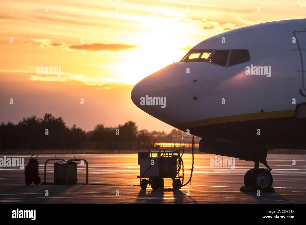 Blick auf die Seite des geparkten Flugzeugs mit Hintergrundbeleuchtung, Sonnenuntergangszeit. Kleinkarosserie-Jet-Flugzeug Stockfoto