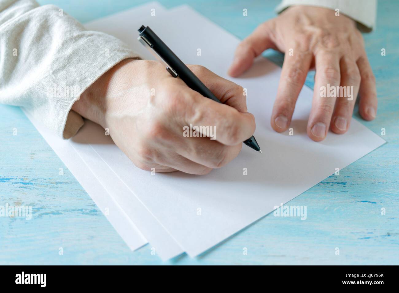 Ein Stift in der Hand eines Mannes. Weißes Blatt Papier. Signieren eines Dokuments. Stockfoto