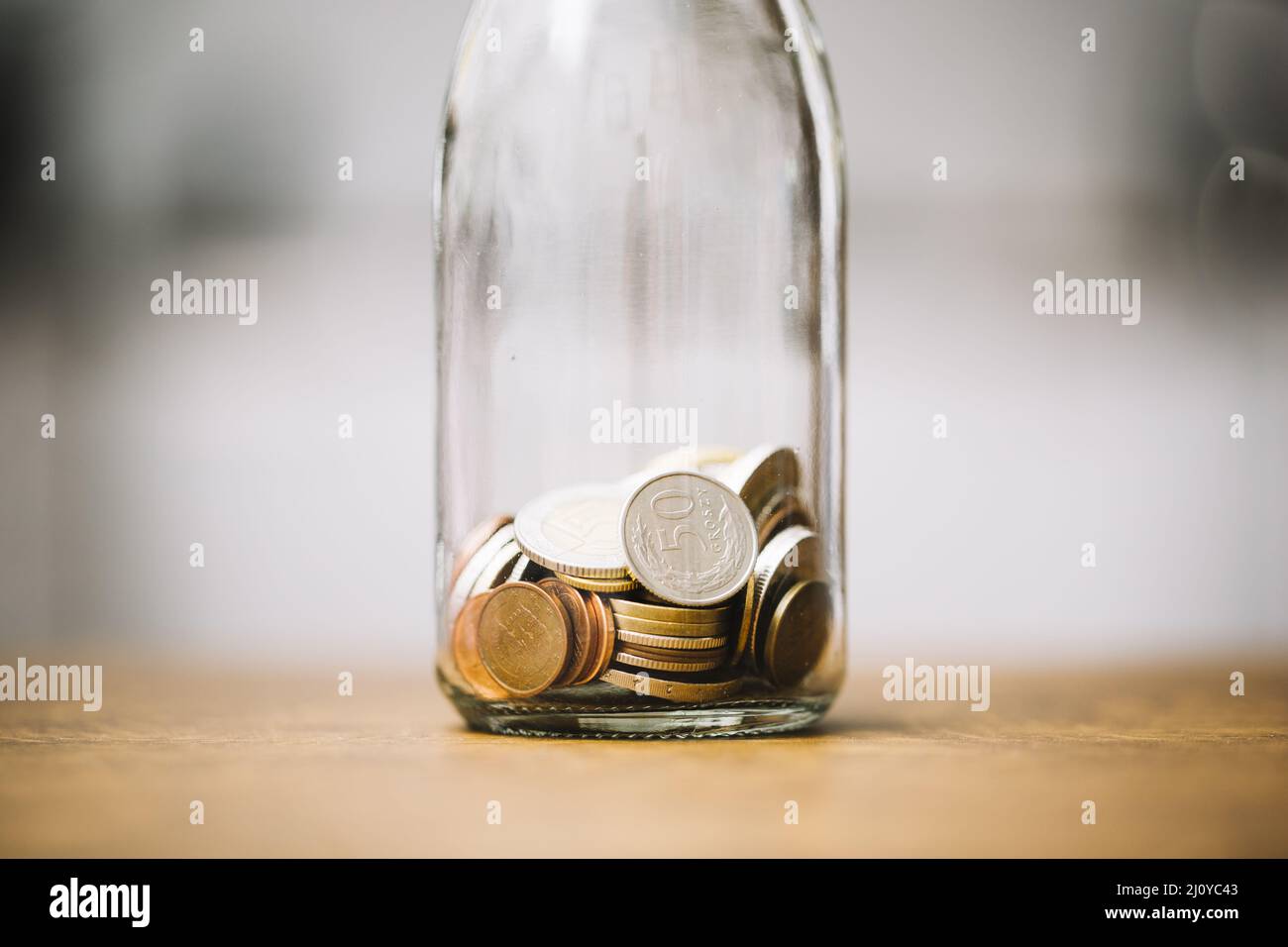 Münzen Glasflasche hölzerne Oberfläche. Hochwertige Fotos Stockfoto
