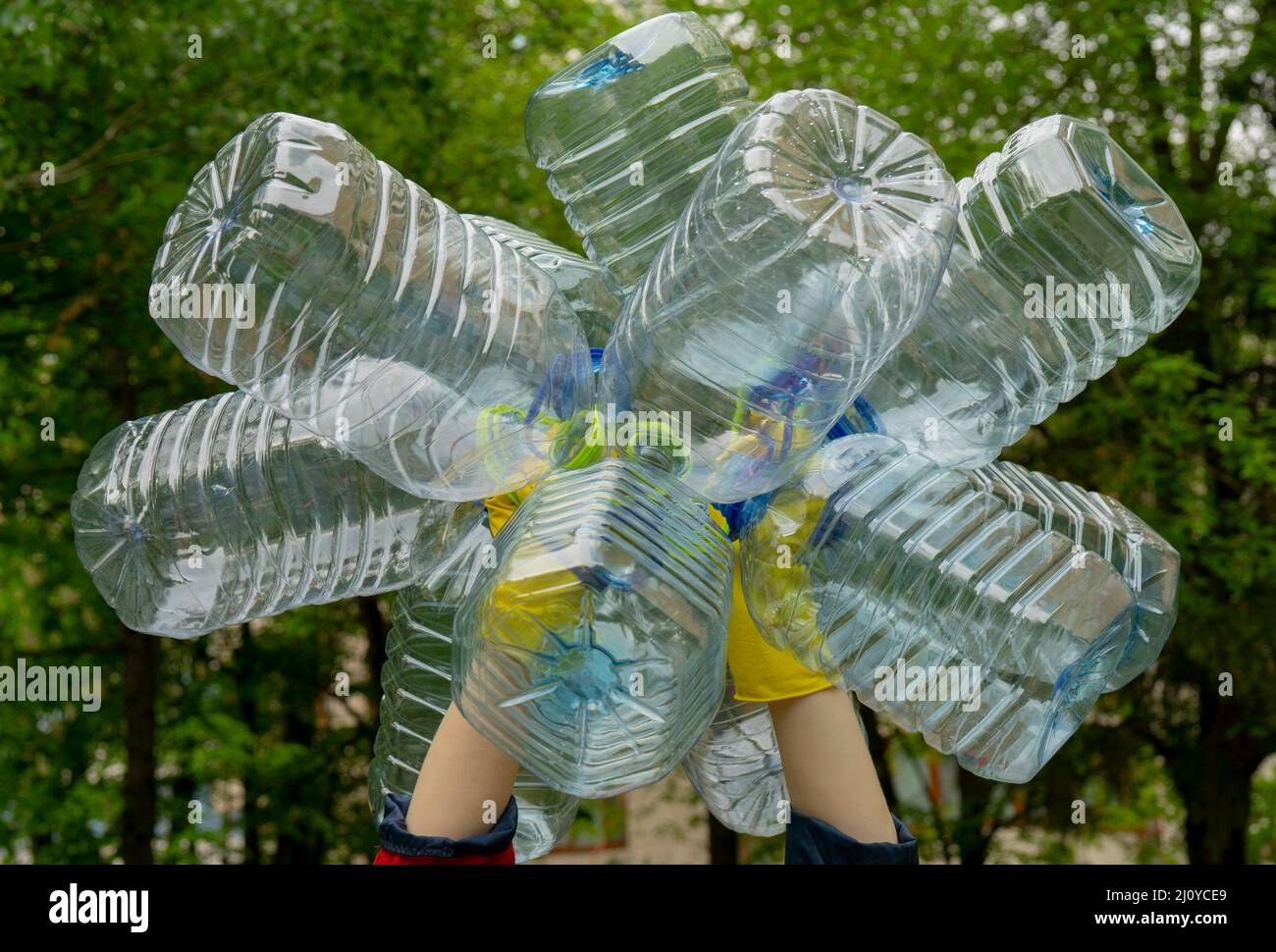 Garbage Collection. Hände in gelb Handschuhe halten große leere Plastikflaschen. Gras auf einem Hintergrund. Stockfoto