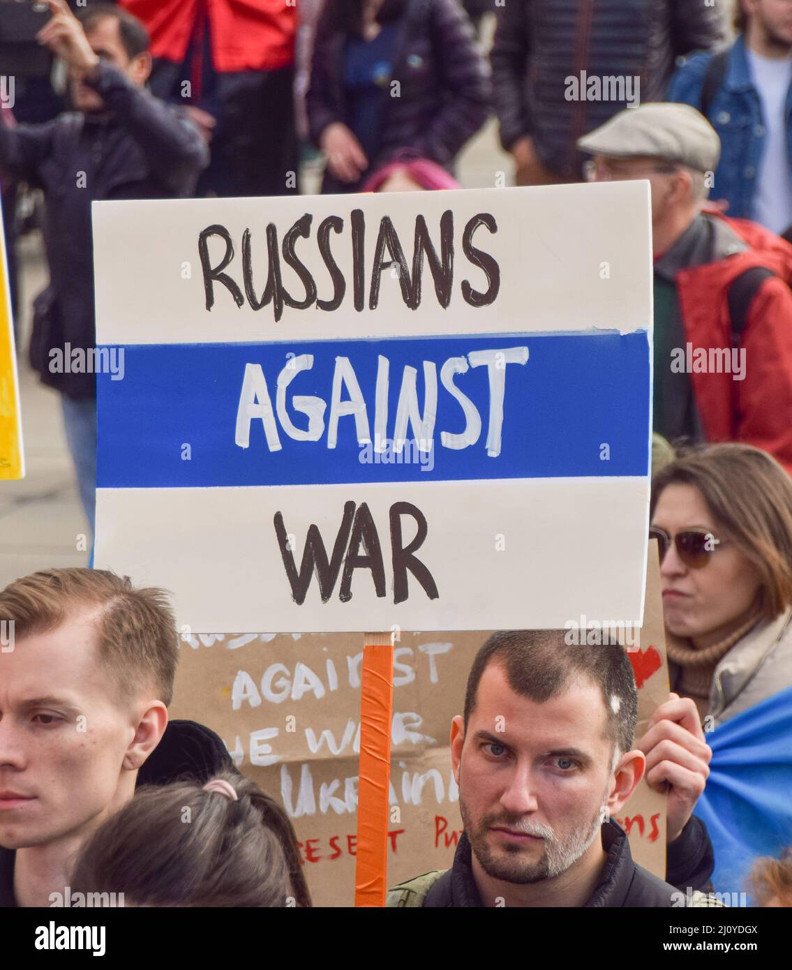 London, Großbritannien. 20.. März 2022. Ein Protestler hält ein Schild mit einer symbolischen russischen Flagge mit blauen und weißen Farben, und das rote entfernt, und die Worte "Russen gegen den Krieg". Auf dem Trafalgar-Platz versammeln sich weiterhin große Menschenmengen zur Unterstützung der Ukraine, während Russland seinen Angriff verstärkt. Stockfoto