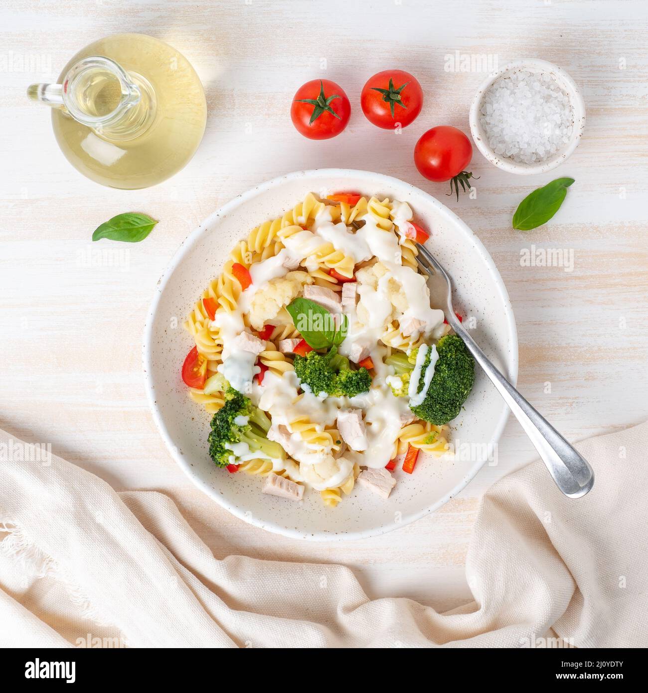 Nudelfusilli mit Gemüse, gekochtem gedämmtem Fleisch, weißer Soße auf weißem Holztisch, kalorienarme Speisen, fettarme Ernährung, Draufsicht Stockfoto