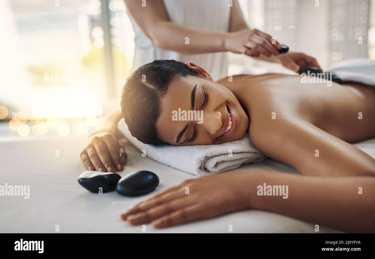 Das ist so entspannend. Aufnahme einer jungen Frau, die in einem Spa eine Hot-Stone-Massage bekommt. Stockfoto