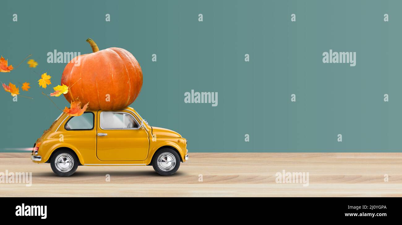 Thanksgiving kommt. Gelbes Auto trägt einen Kürbis Stockfoto