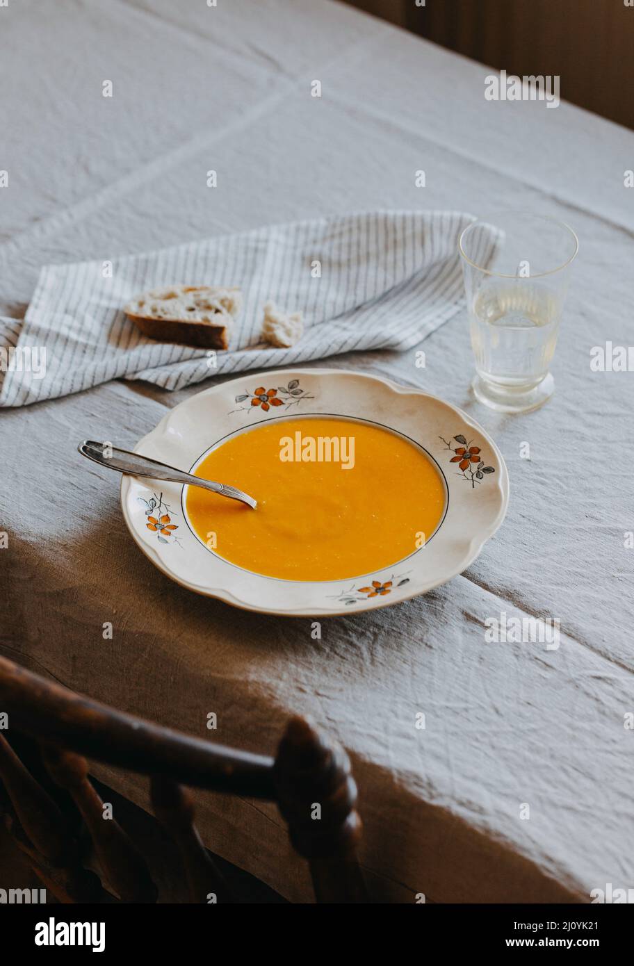 Eine Schüssel Karottensuppe auf einer beigefarbenen Leinentischdecke Stockfoto