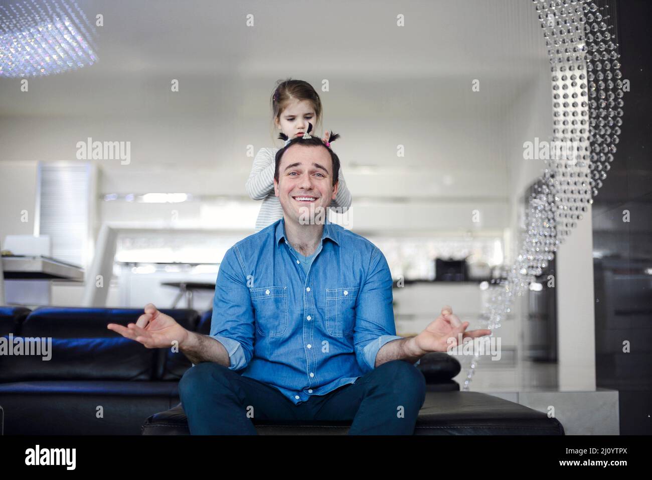 Junge Brünette Mann mit seiner niedlichen kleinen Tochter zu Hause. Fröhlicher Vater spielt mit Tochter in einer modernen Wohnung zusammen und wird lustig kreativ Stockfoto