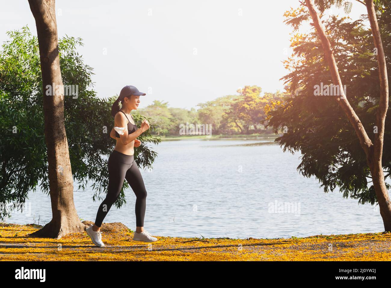 Seitenansicht der Frau beim Laufen im Park in der Nähe des Sees am Morgen. Stockfoto