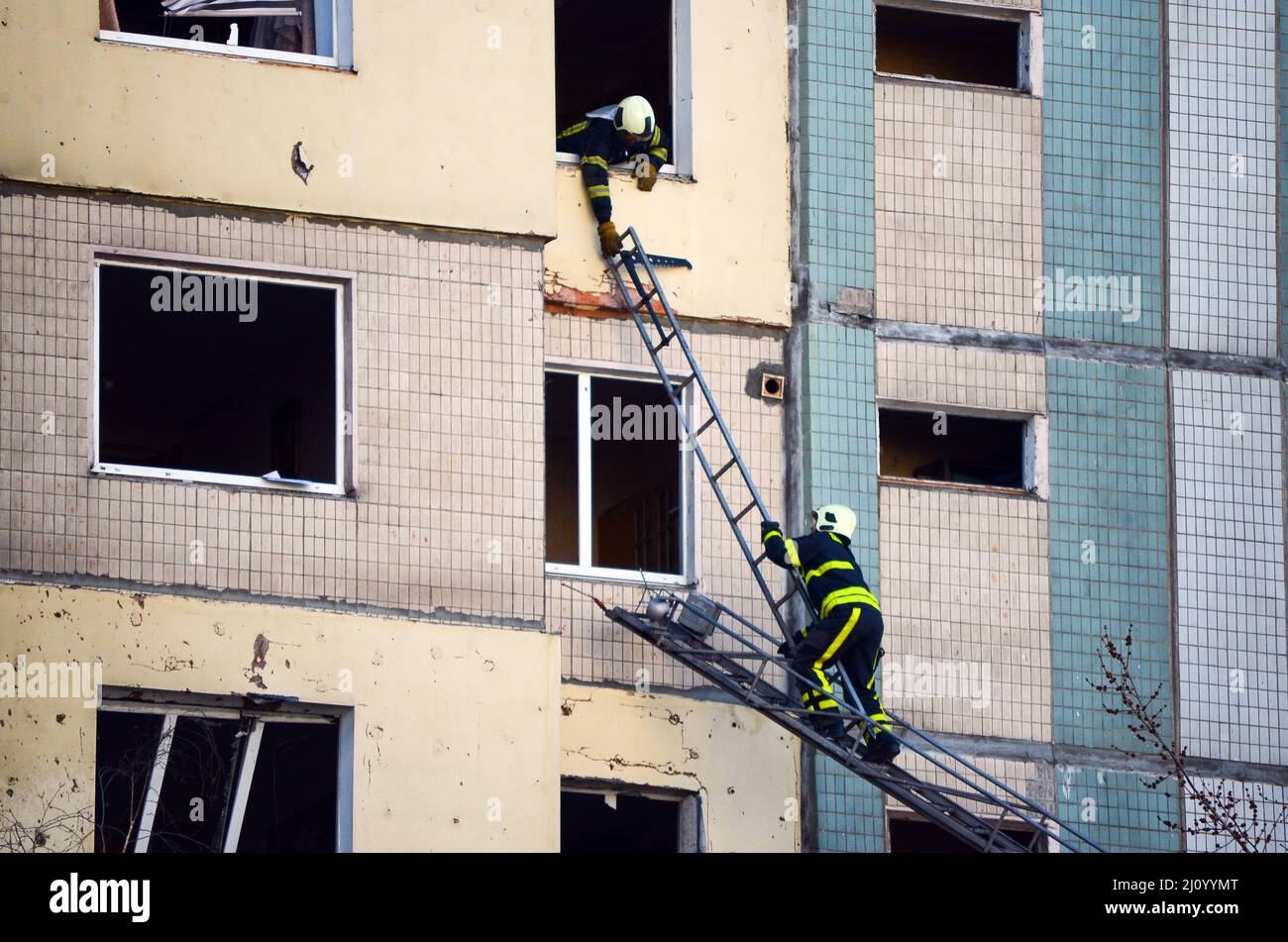 KIEW, UKRAINE - 20. MÄRZ 2022 - während einer Reaktion auf den Beschuss eines Wohngebiets in Sviato passieren Rettungskräfte eine Leiter, um eine Wohnung zu erreichen Stockfoto