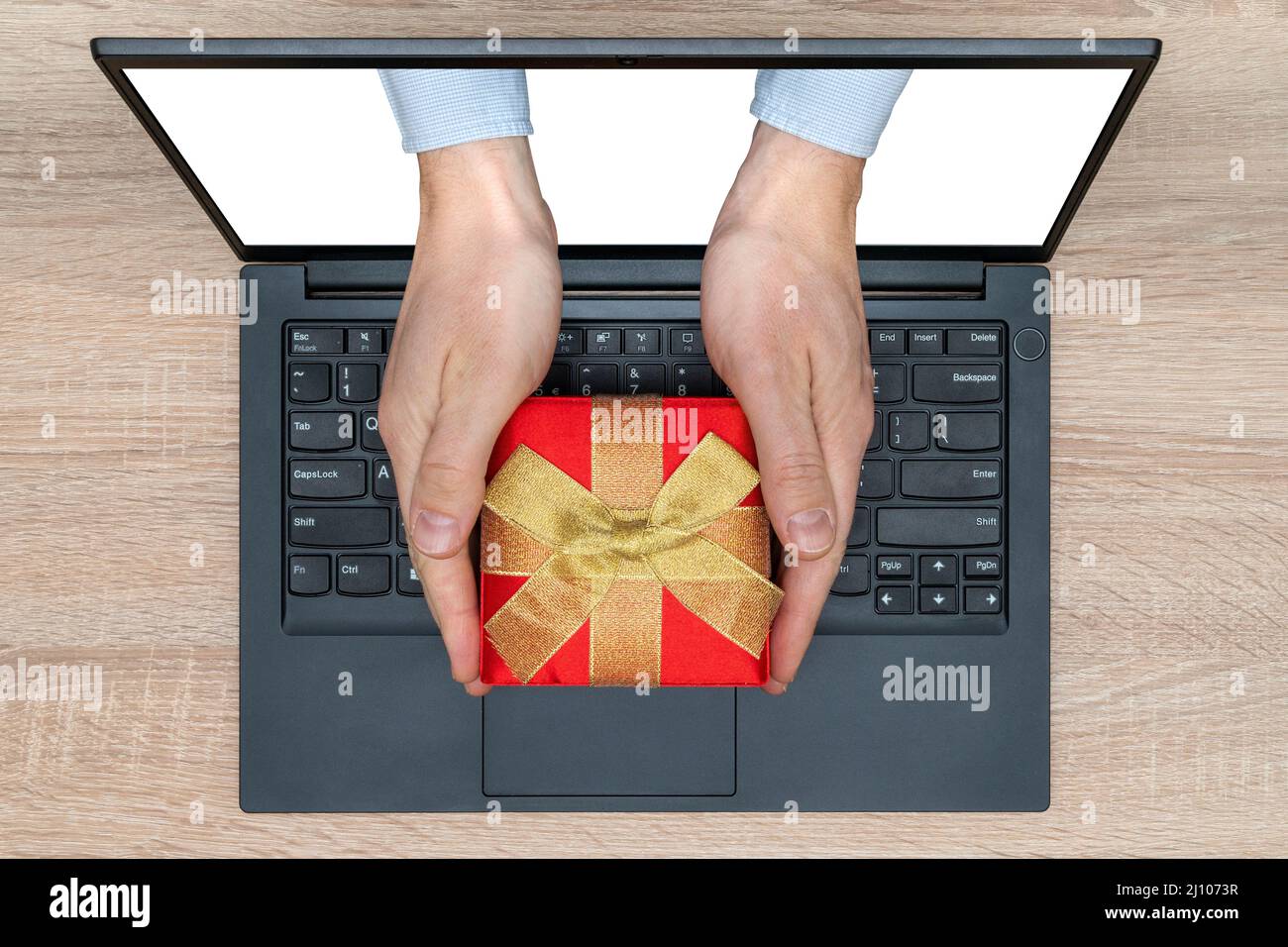 Hände mit einem Geschenk kommen von einem Bildschirm eines Laptops. Stockfoto