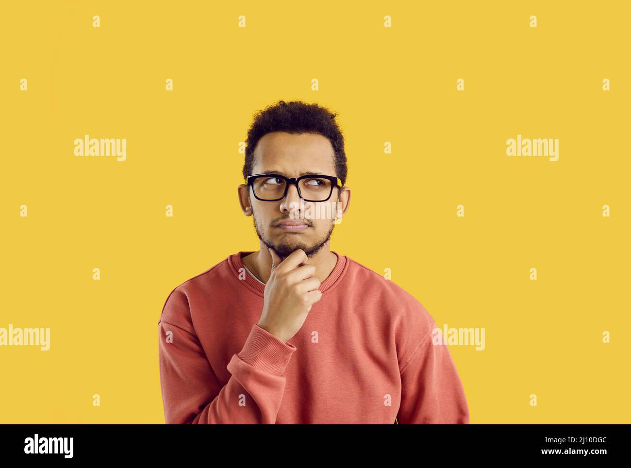 Verwirrt Student in Brille zweifelt etwas und denken hart mit der Hand auf dem Kinn Stockfoto