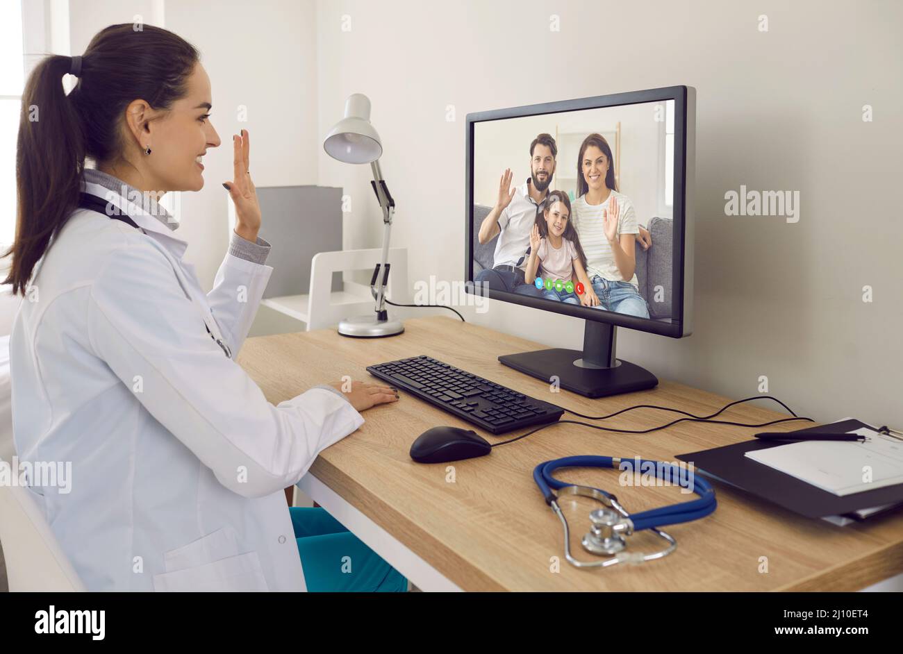 Glücklicher Arzt mit Online-Beratung mit der ganzen Familie per Videoanruf am Computer Stockfoto
