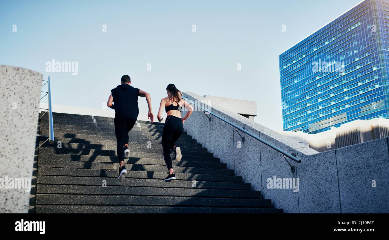 Tun Sie, was immer Ihr Blut fließt. Rückansicht eines jungen Mannes und einer jungen Frau, die zusammen in der Stadt Treppen hochlaufen. Stockfoto