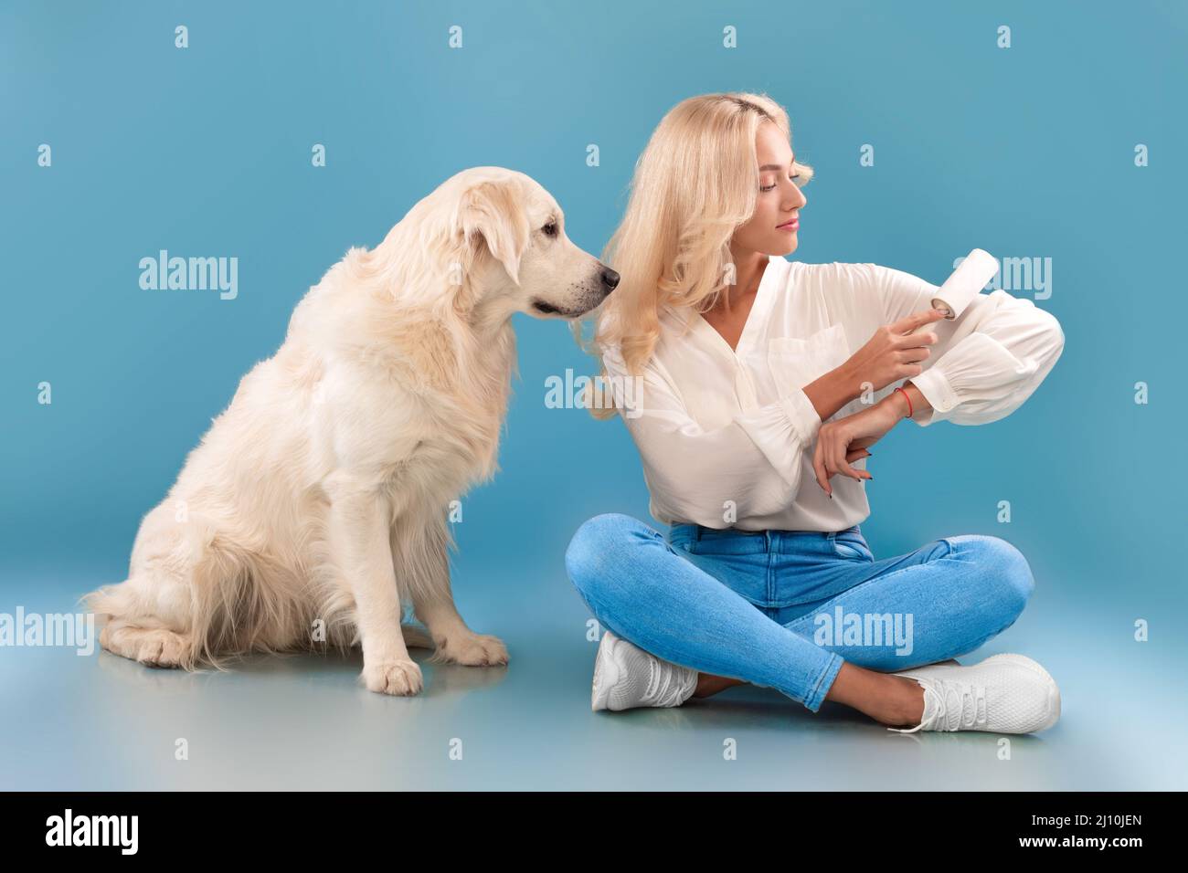 Frau, die ihre Kleidung mit einer Haftwalze vom Hundepelz säubert Stockfoto