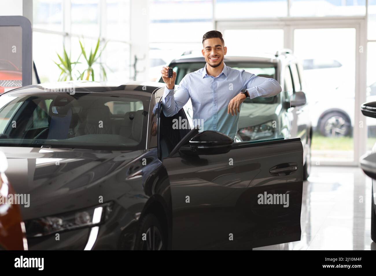 Wohlhabender arabischer Mann Geschäftsmann, der ein neues Auto kauft und Schlüssel zeigt Stockfoto