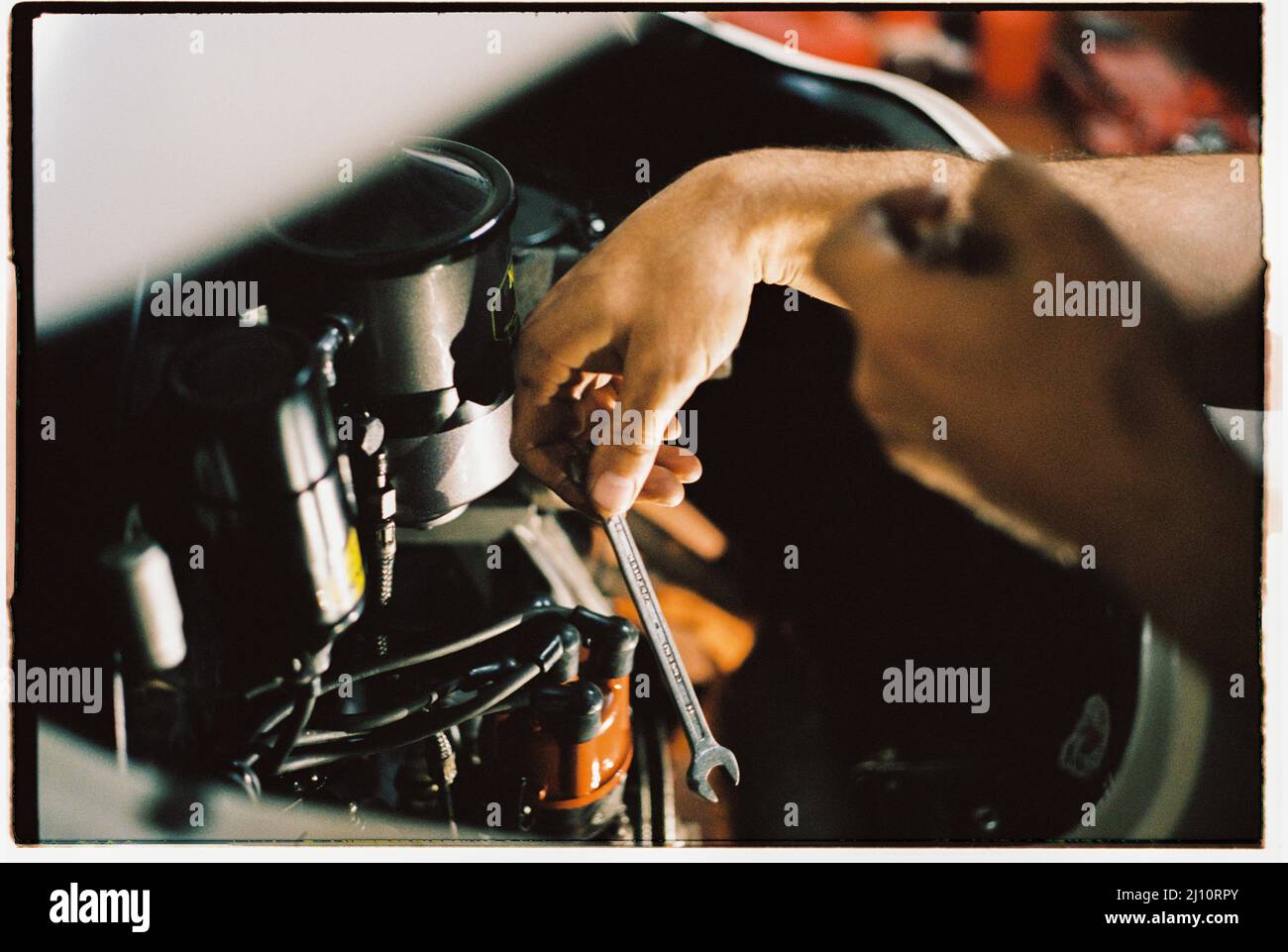 Mechanische Hand mit einem Schraubenschlüssel, der an einem Oldtimer-Motor arbeitet Stockfoto