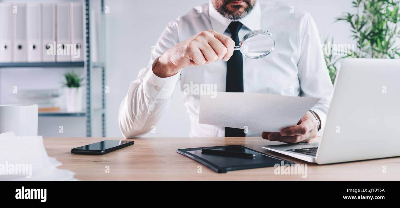 Steuerinspektor und Finanzprüfer schauen durch die Lupe, überprüfen Unternehmenspapiere, Dokumente und Berichte, selektiver Fokus Stockfoto