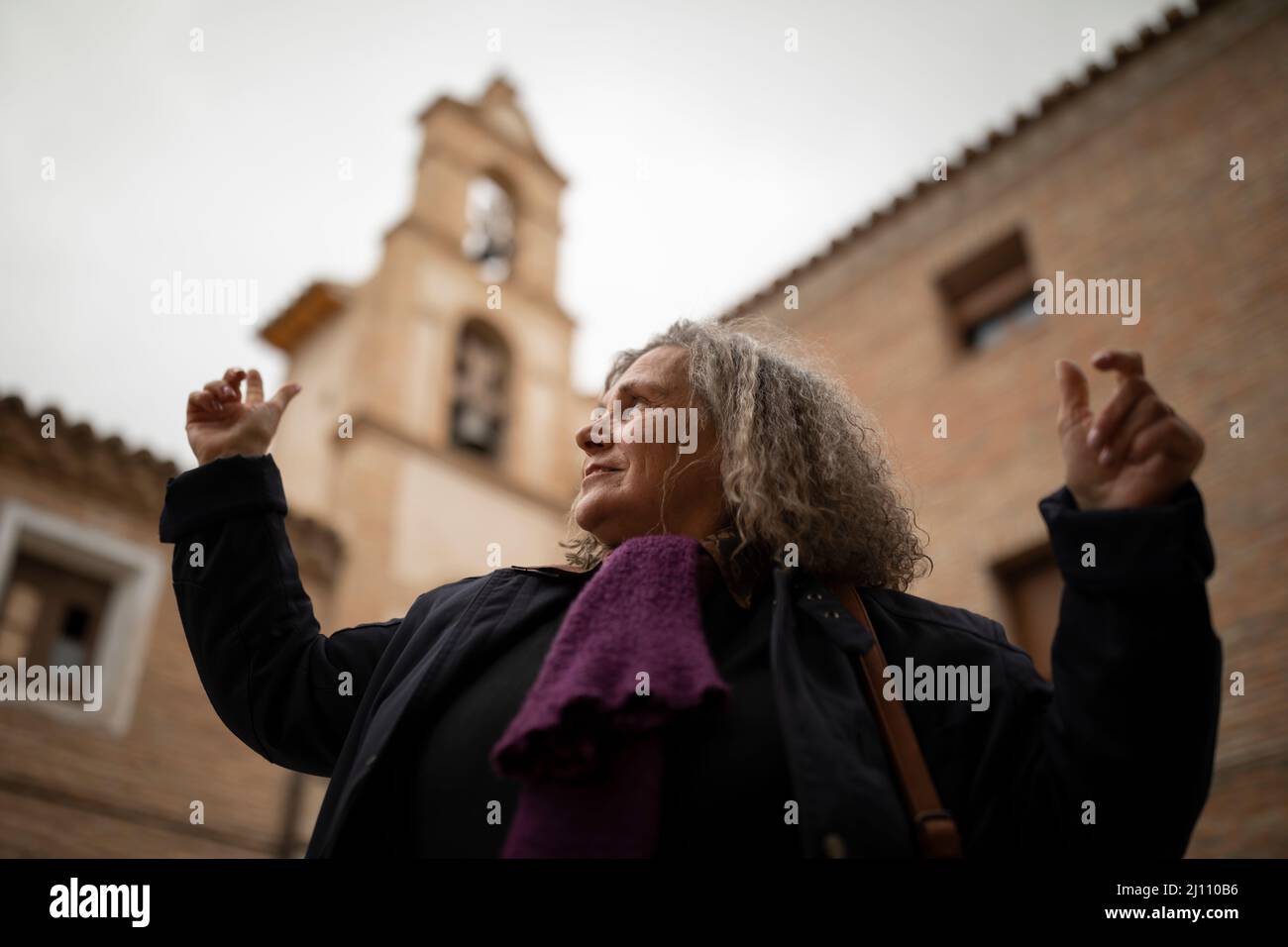 Eine Frau mit grauen Haaren genießt die Architektur und den Blick vom Glockenturm der Kirche der Heimsuchung in Malejan während eines ländlichen Tourismus geta Stockfoto