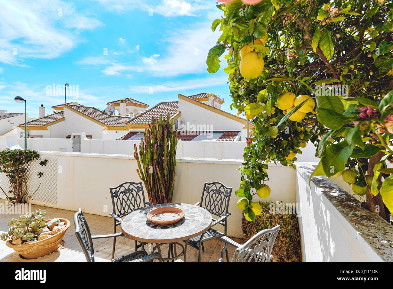 Nette Terrasse mit leerem Tisch und Stühlen und blühendem Zitronenbaum. Spanien Stockfoto