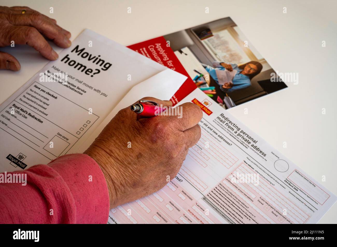 Dame, die ein Postanschrift-Formular für den Umzug auf weißem Hintergrund ausfüllt Stockfoto