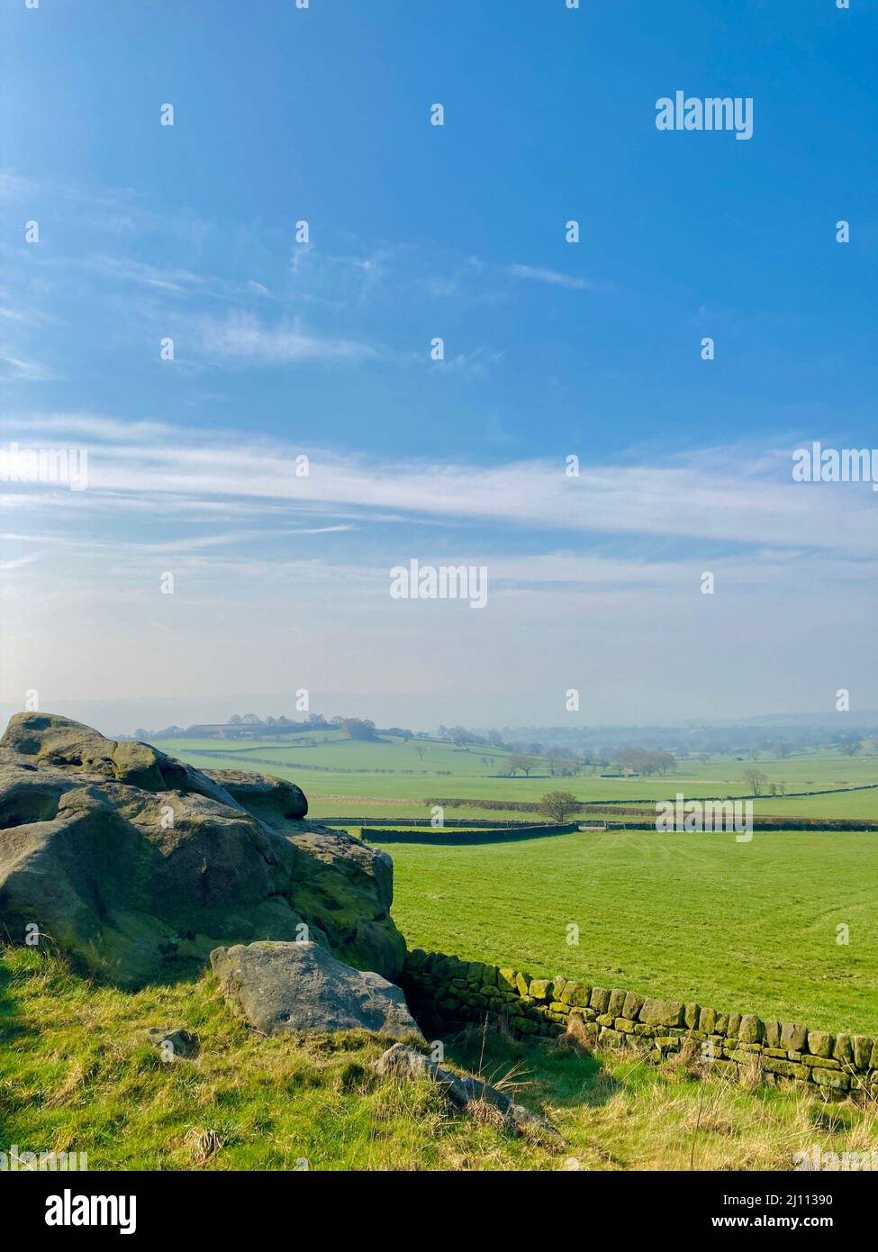 Landschaftlich schöner blauer Himmel über grünen Feldern von Almscliffe Crag aus, einem Mühlstein-Grit-Ausbiß in der Landschaft von North Yorkshire. Stockfoto