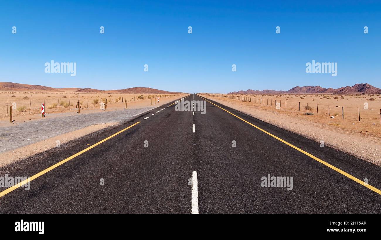 Asphaltierte Autobahn, die durch die trockene, trockene Landschaft der Namib-Wüste in Namibia führt Stockfoto