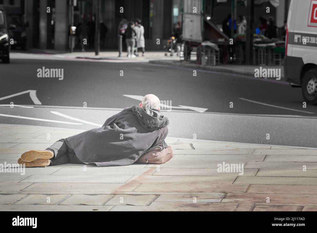 Ein Mann legt sich auf den Bürgersteig in der Victoria Street, London, England. Stockfoto