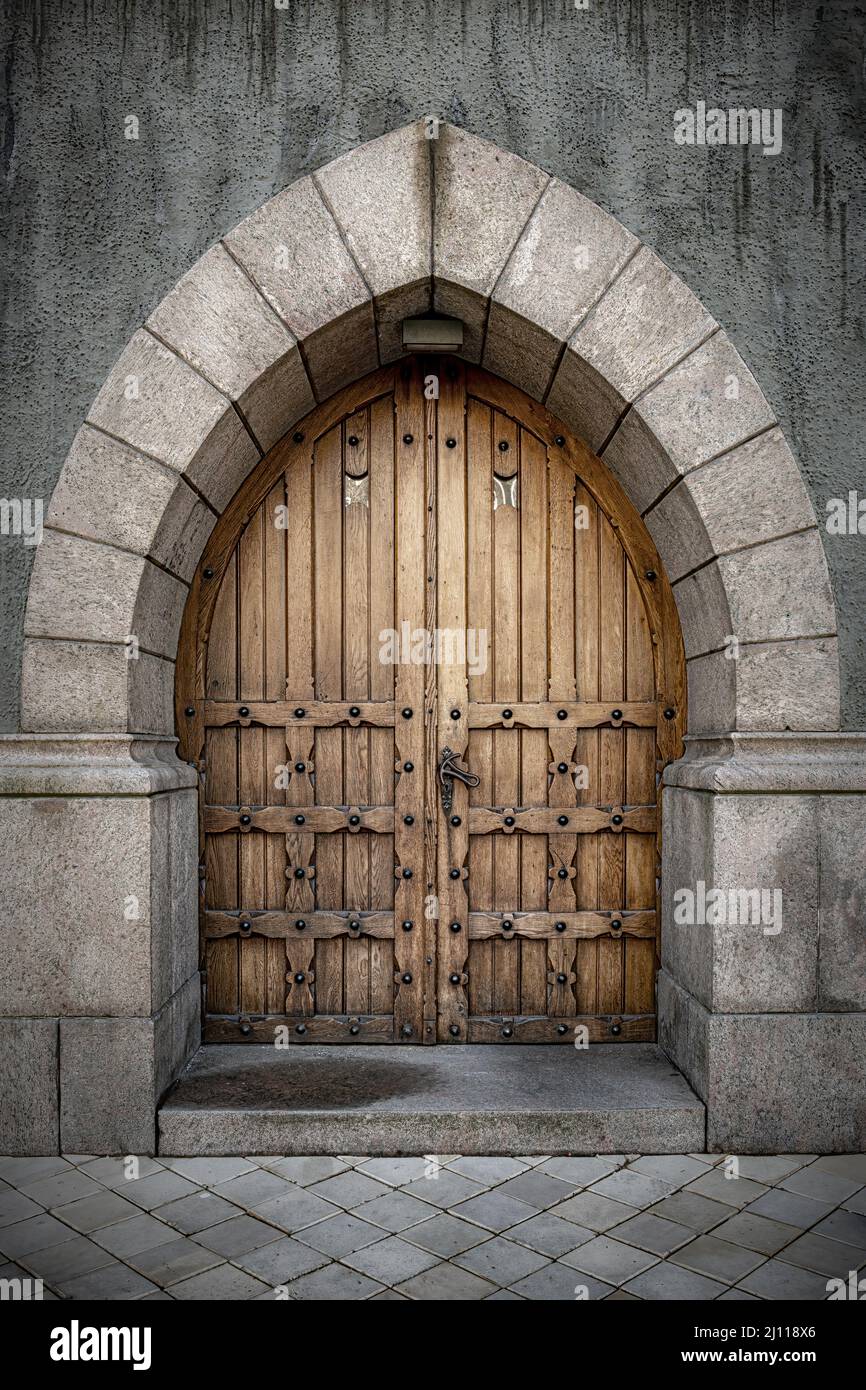 Ein Steinbogen mit Doppeltüren aus Eiche mit eisernen Nieten für einen klassischen Gothic-Look. Stockfoto