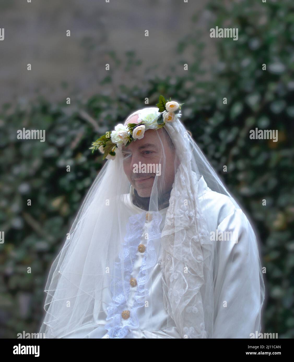 Enciso, Spanien – 5. März 2022: Schüchterner Mann in einem weißen Hochzeitskleid und Blumenkrone auf dem Kopf, der wegschaut. Traditioneller Karneval von Enciso. Stockfoto