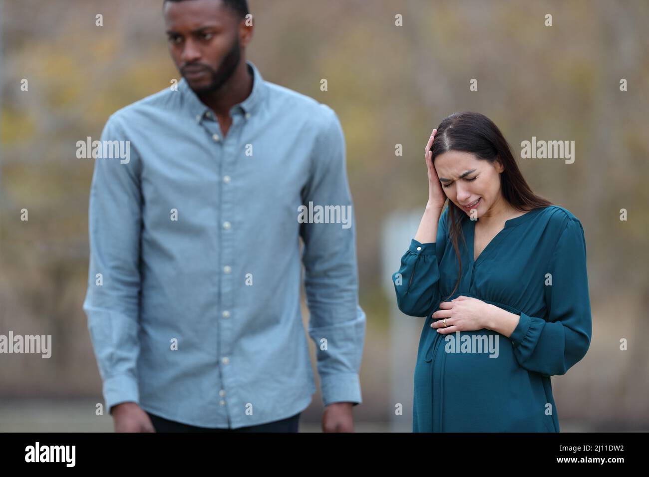 Vorderansicht Porträt einer Trennung mit einem Mann, der seine traurige, schwanger Frau in einem Park lässt Stockfoto