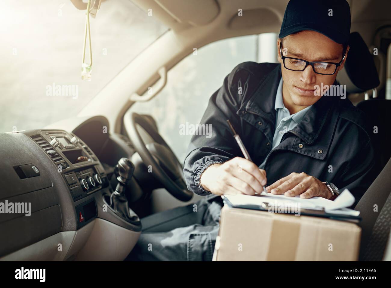 Überprüfen, wo sein nächster Lieferstopp ist. Aufnahme eines Kuriers, der in seinem Lieferwagen Lieferungen abgibt. Stockfoto