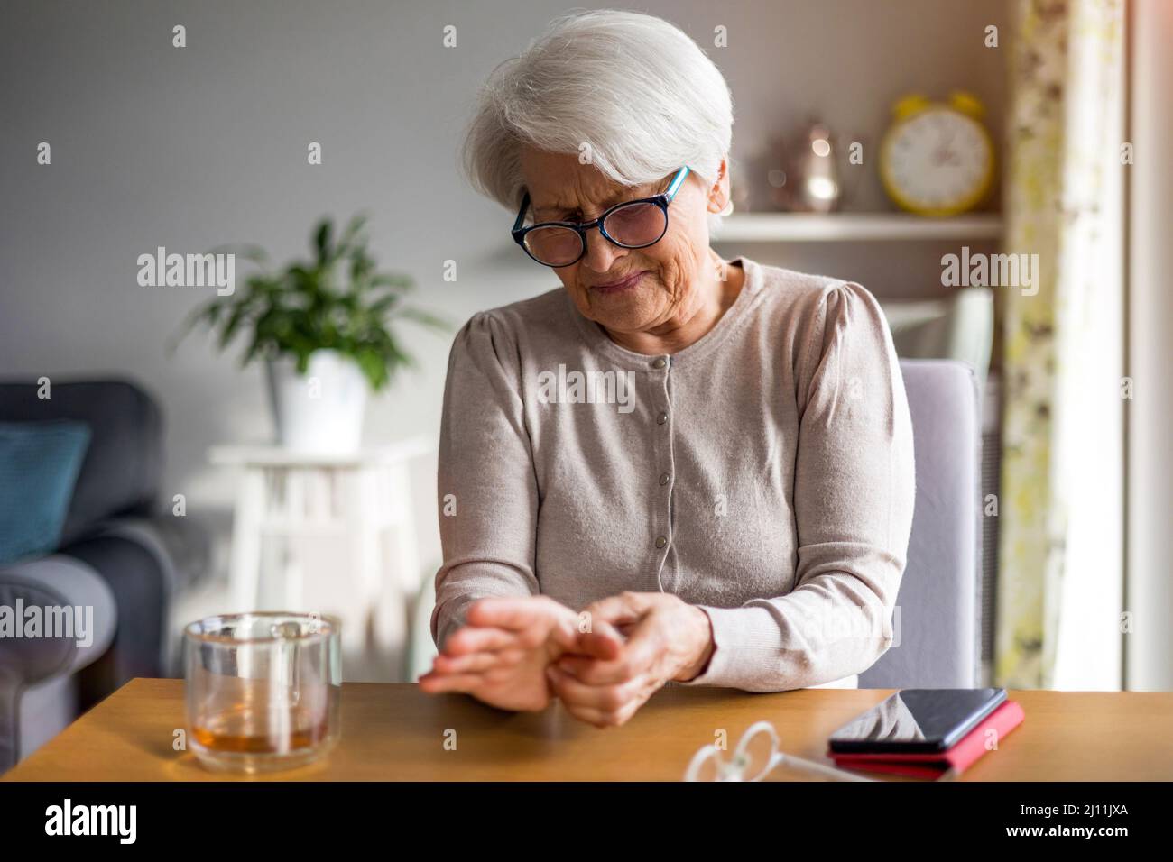 Ältere Frau mit reibenden Händen der Arthritis Stockfoto