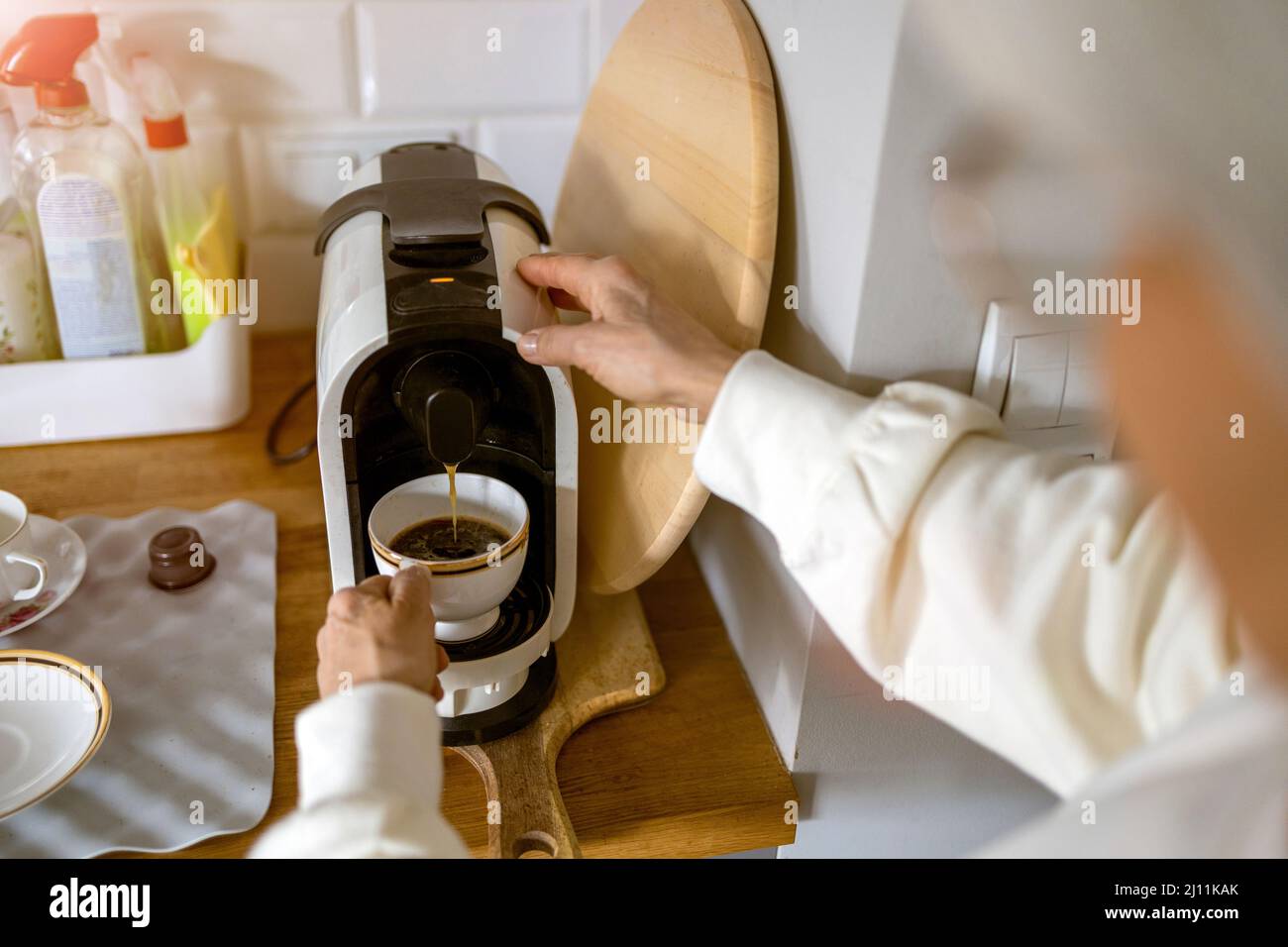 Nahaufnahme einer älteren Frau, die mit einer Espressomaschine zu Hause Kaffee zubereitet Stockfoto
