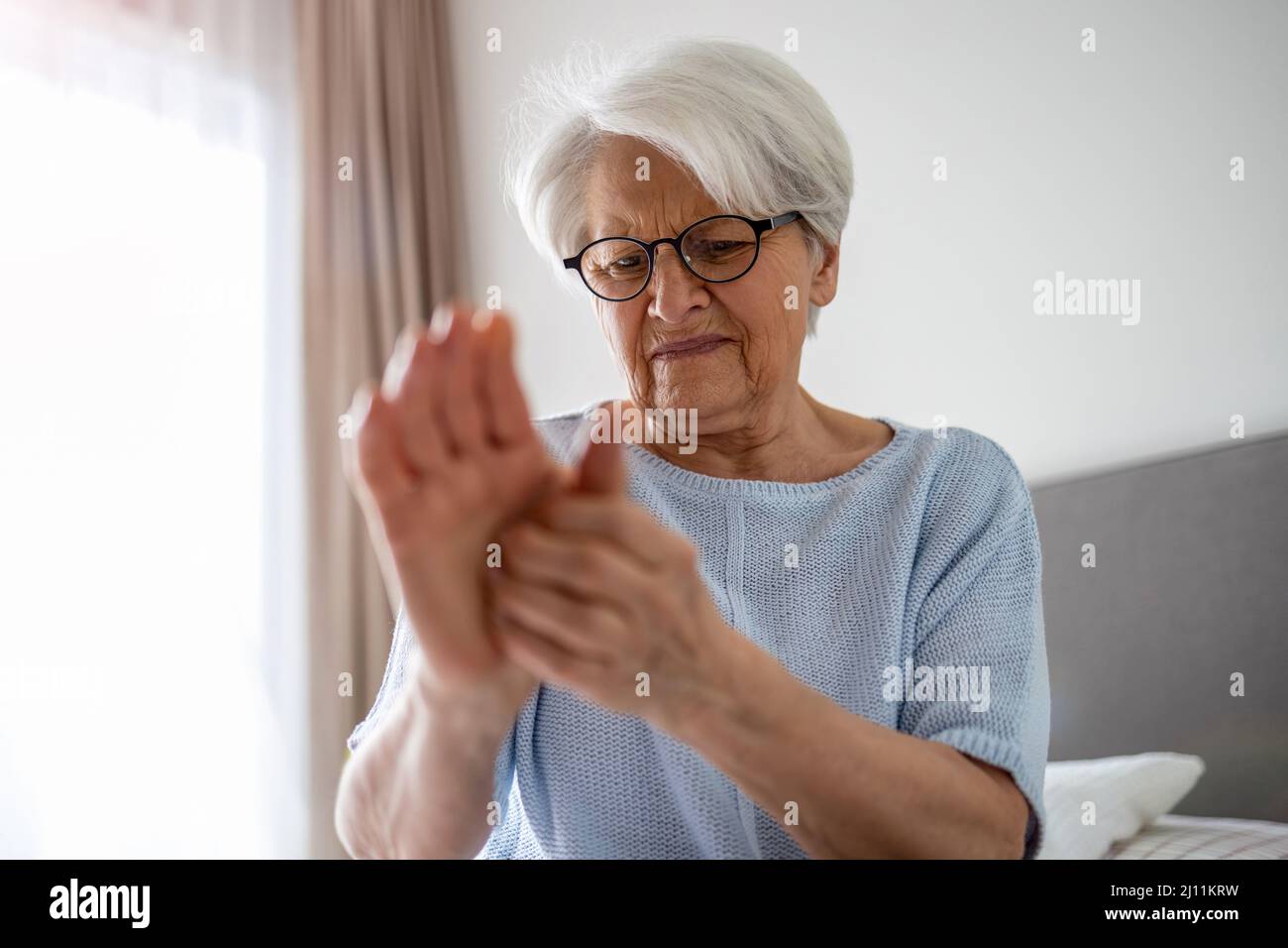 Ältere Frau mit reibenden Händen der Arthritis Stockfoto
