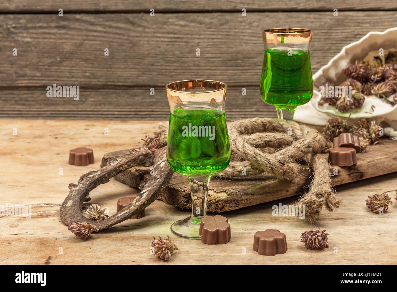 St. Patrick's Day Konzept. Traditioneller grüner Cocktail, süße Schokolade in Form von Kleeblättern, Hufeisen, Vintage-Seil. Traditionelle festliche dez Stockfoto