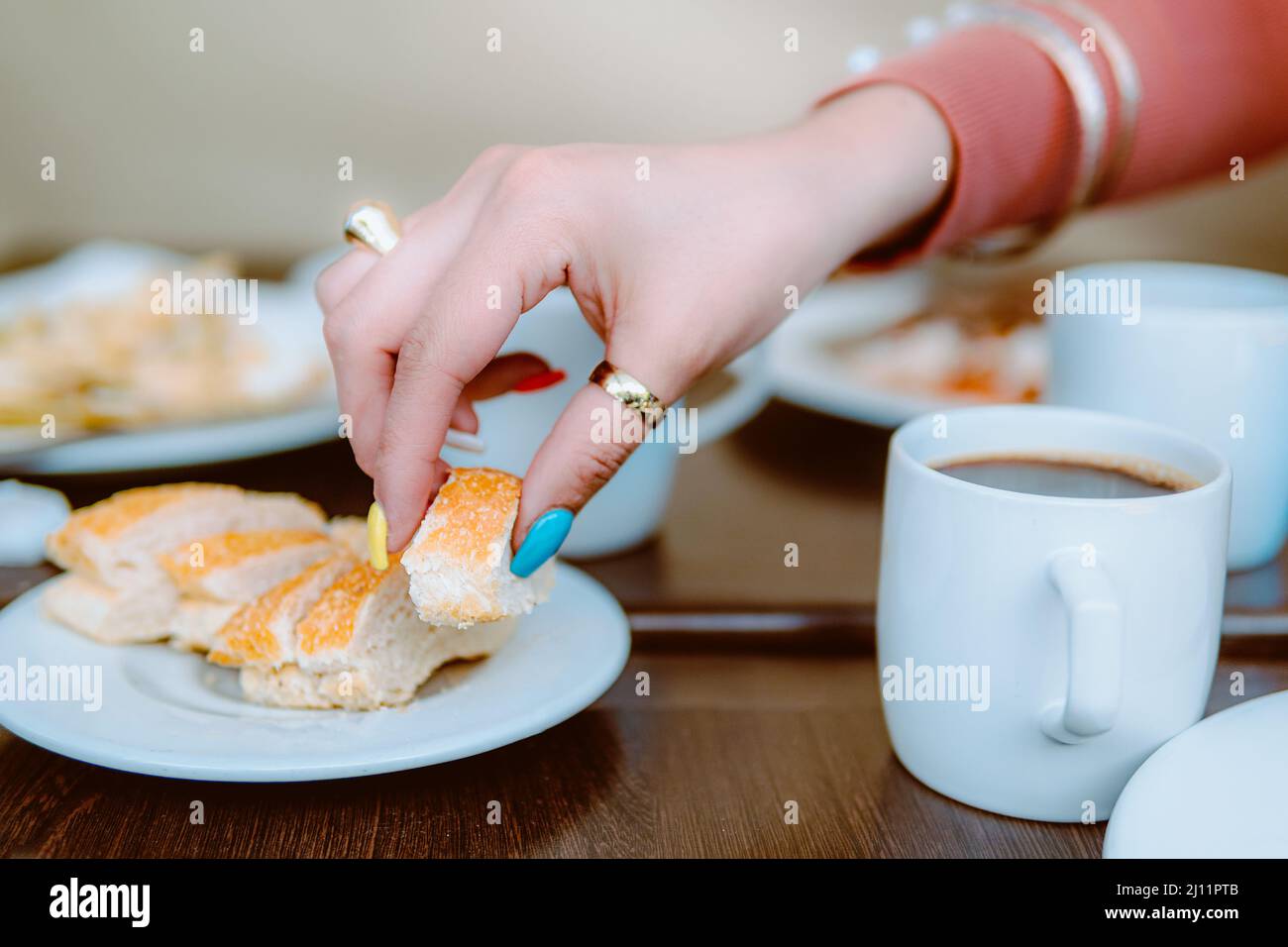 Nahaufnahme der Hand einer Frau, während sie an einem Restauranttisch nach einem Laib Brot greift Stockfoto