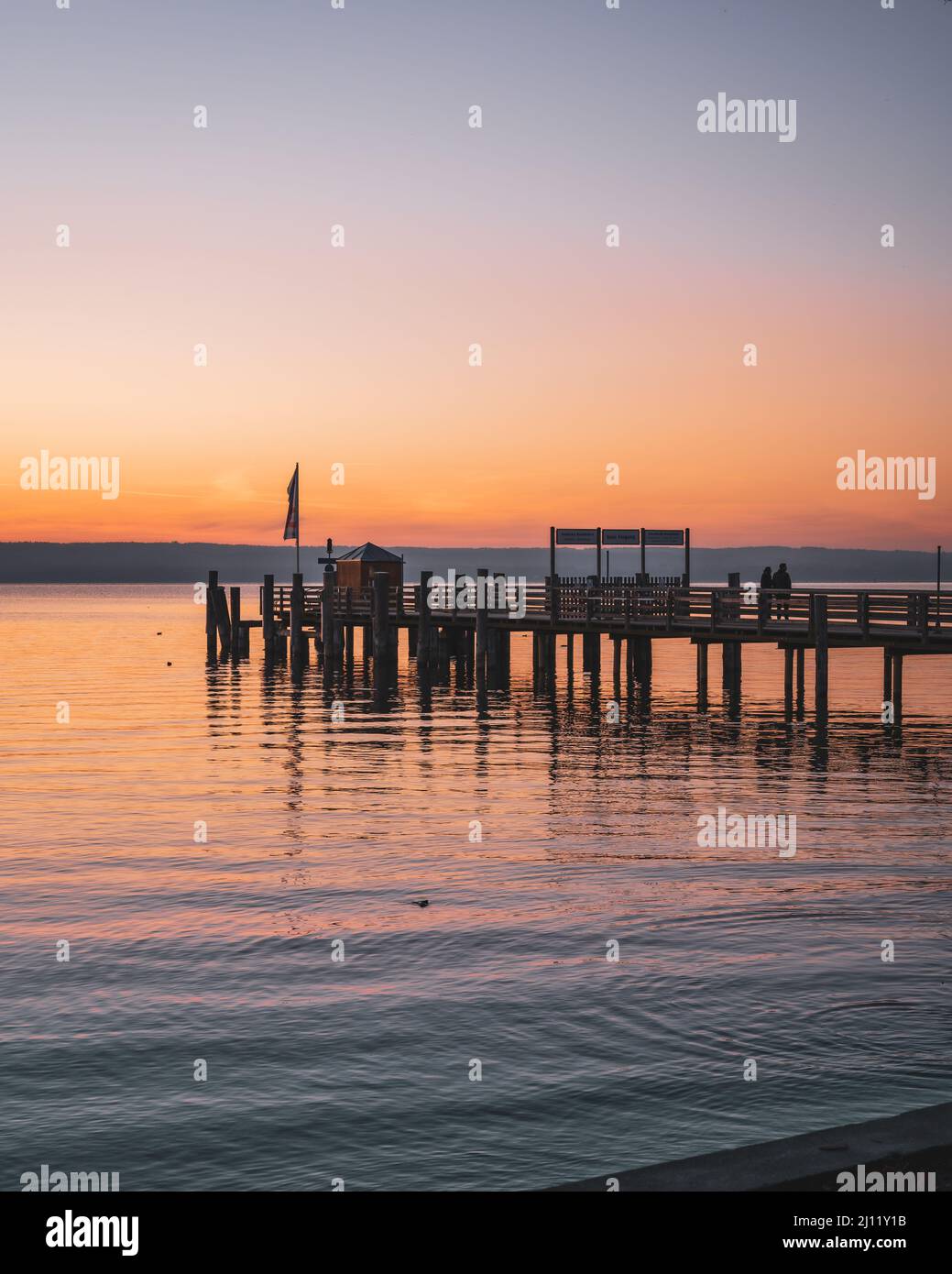 Vertikale Aufnahme eines hölzernen Docks am Meer bei Sonnenuntergang in München, Bayern Stockfoto