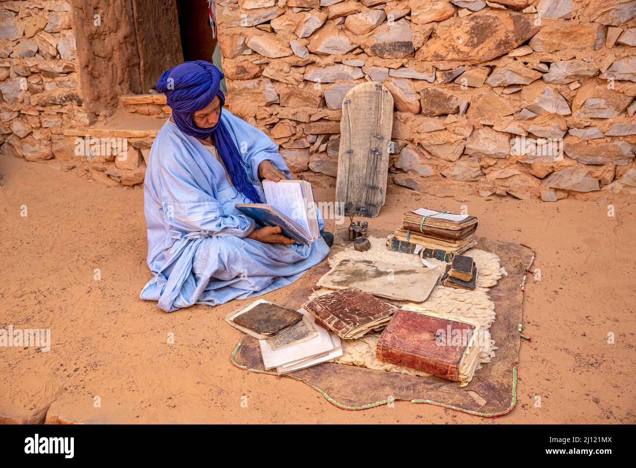 Mauretanischer Mann mit traditionellem blauen Boubou und Turban und alten islamischen Büchern in einer alten Bibliothek, Chinguetti, Mauretanien Stockfoto