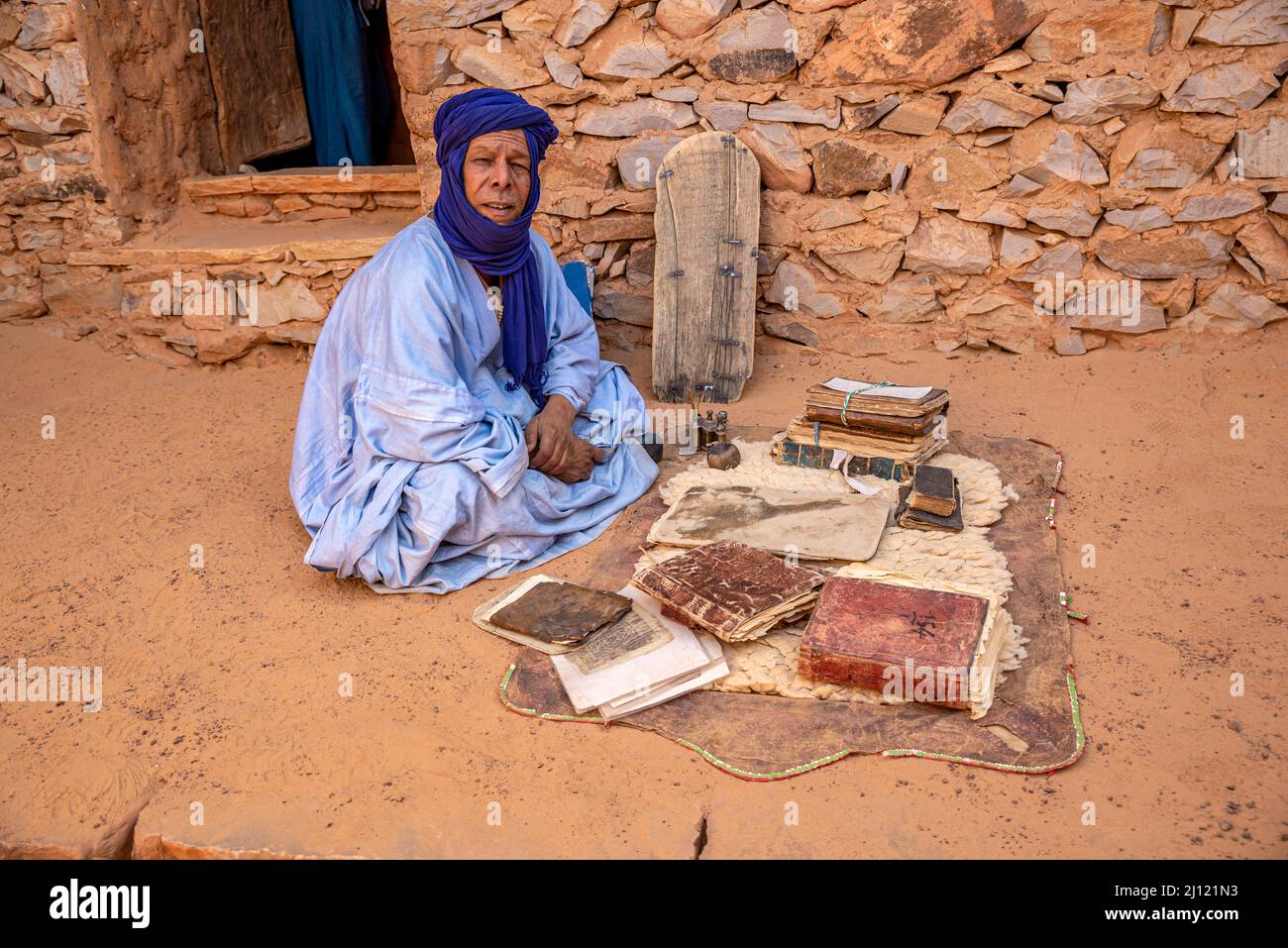 Mauretanischer Mann mit traditionellem blauen Boubou und Turban und alten islamischen Büchern in einer alten Bibliothek, Chinguetti, Mauretanien Stockfoto