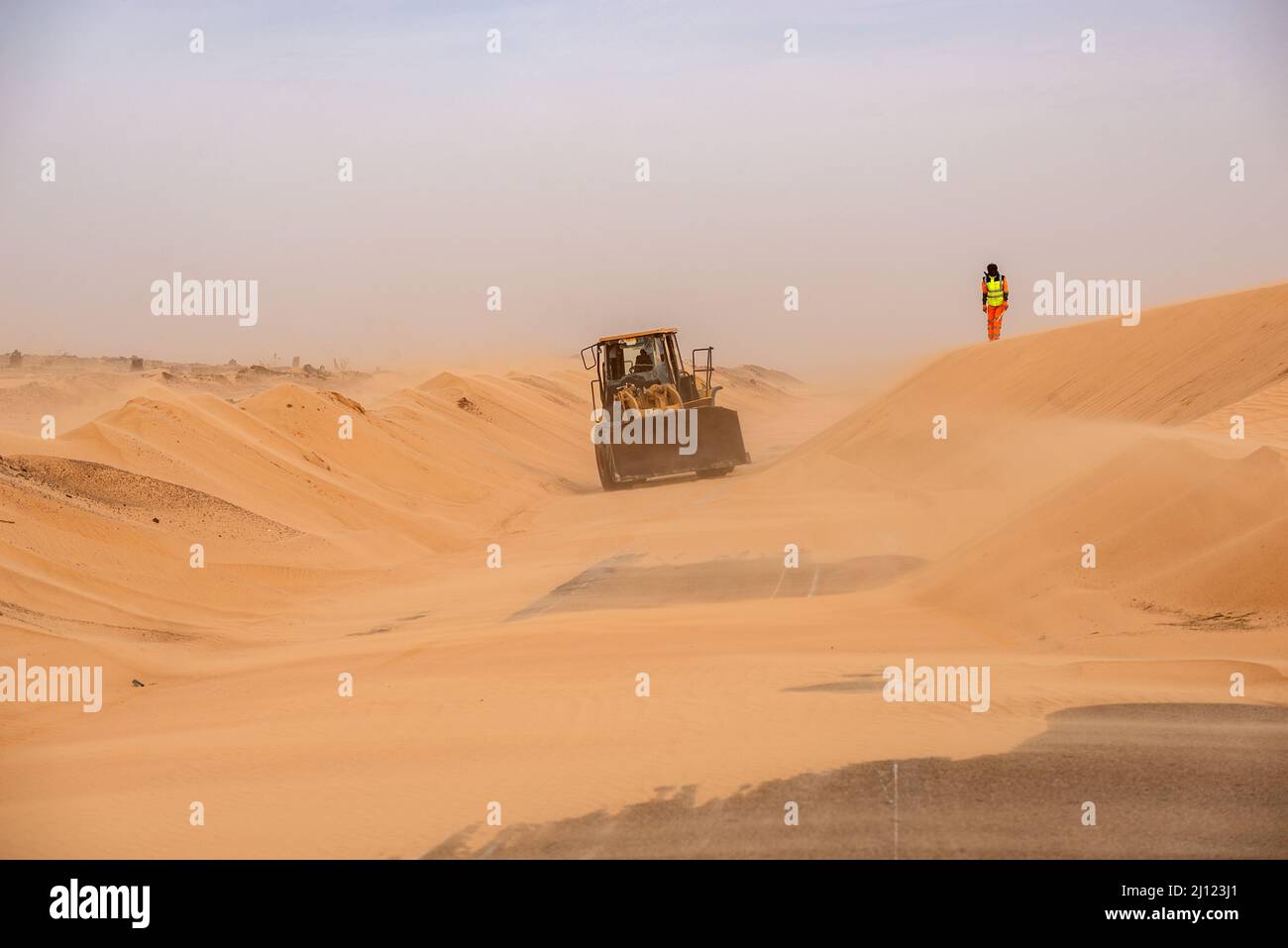 Ein Bulldozer arbeitet, um Wüstensand von der Straße zu entfernen, Adrar Region, Mauretanien Stockfoto