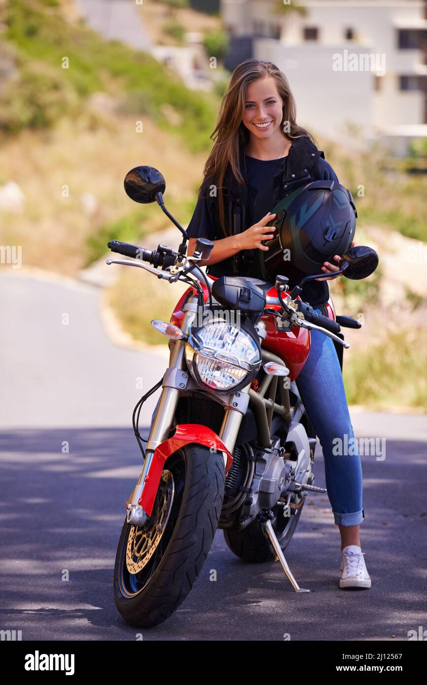 Sind Sie bereit zu fahren. Eine attraktive junge Frau, die ihren Helm auf ihrem Motorrad hält. Stockfoto