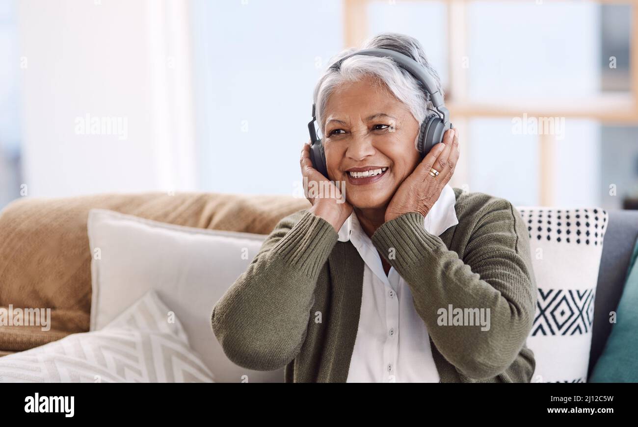 Einige Stücke werden mein Favorit bleiben für immer. Aufnahme einer älteren Frau, die Kopfhörer trägt, während sie zu Hause Musik hört. Stockfoto