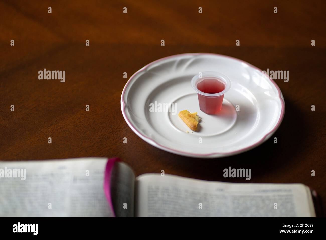 Christliches Abendmahl Sakramente, Wein und Brot mit offener Bibel, auf einem Holztisch. Stockfoto