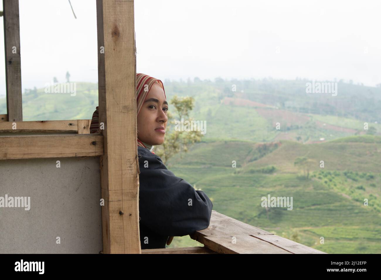 Eine Frau blickt voraus auf eine Teeplantage auf einem hohen Berg. Pangalengan, West-Java, Indonesien Stockfoto