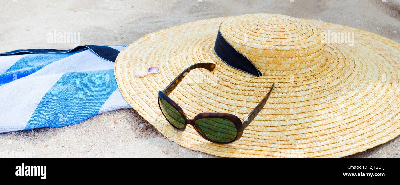 Stroh Frauenhut und Sonnenbrille am Strand. Sommer. Feiertage. Ausflüge. Strandzubehör. Stockfoto