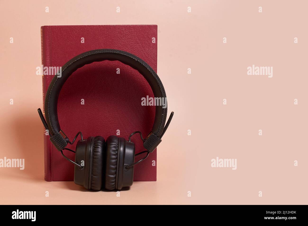 Hörbuch. Kopfhörer stehen neben einem Buch auf einem farbigen Hintergrund Stockfoto